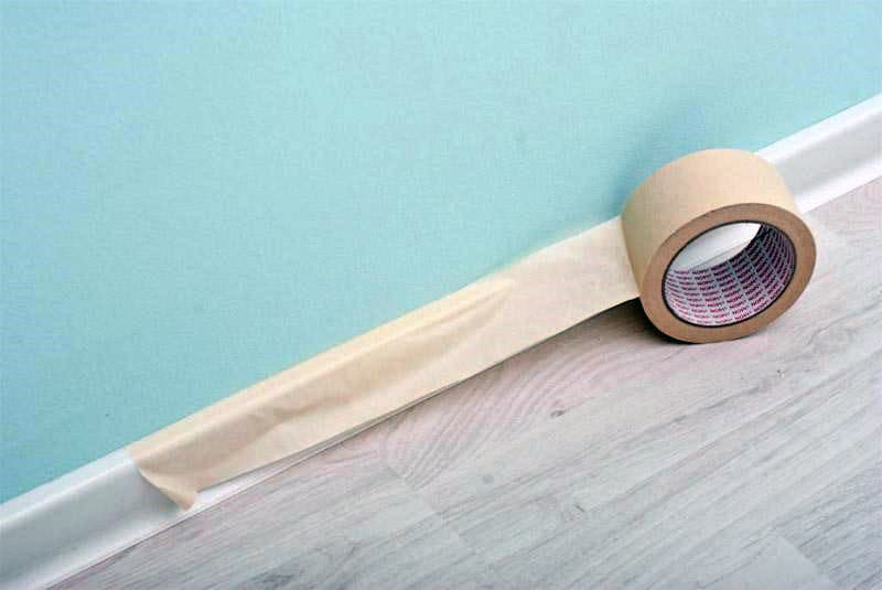 Обклеювання плінтуса скотчем перед фарбуванням стін