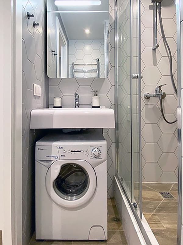 Пральна машина під навісним умивальником у ванній кімнаті