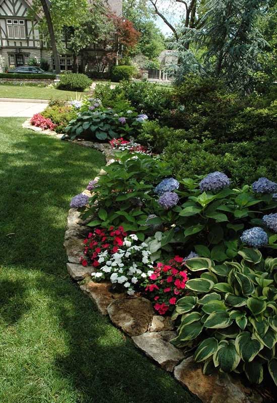 Великий квітник у тіні з кам'яною огорожею