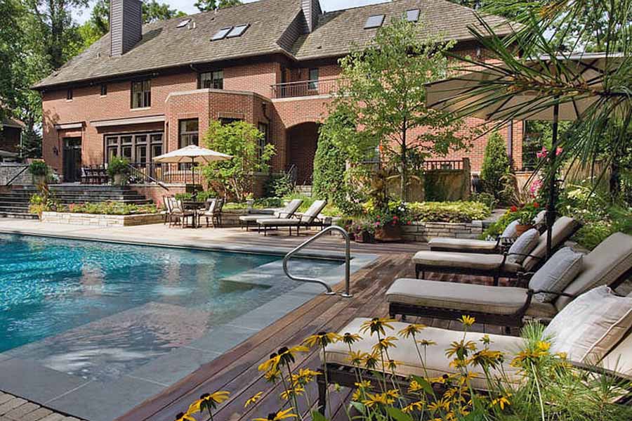 Приклад двору заміського будинку з великим басейном та лаунж-зоною