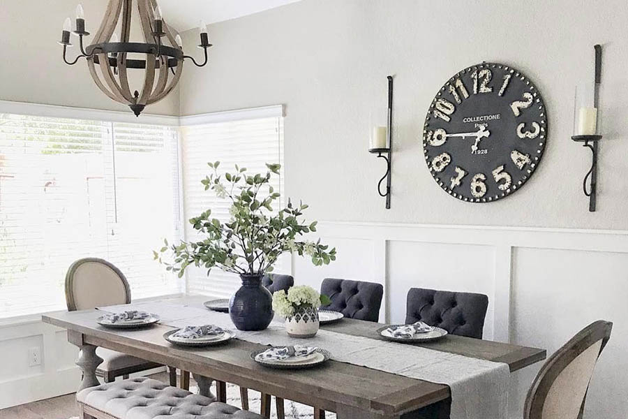 Світла кухня з великим годинником та декораціями на стіні біля столу