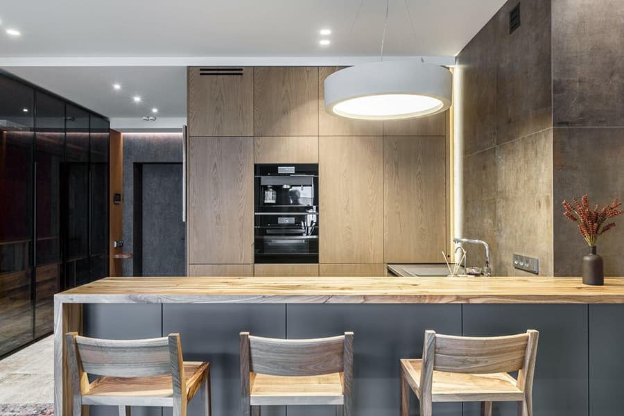 Великий світильник над столовою зоною на кухні з сірим інтер'єром